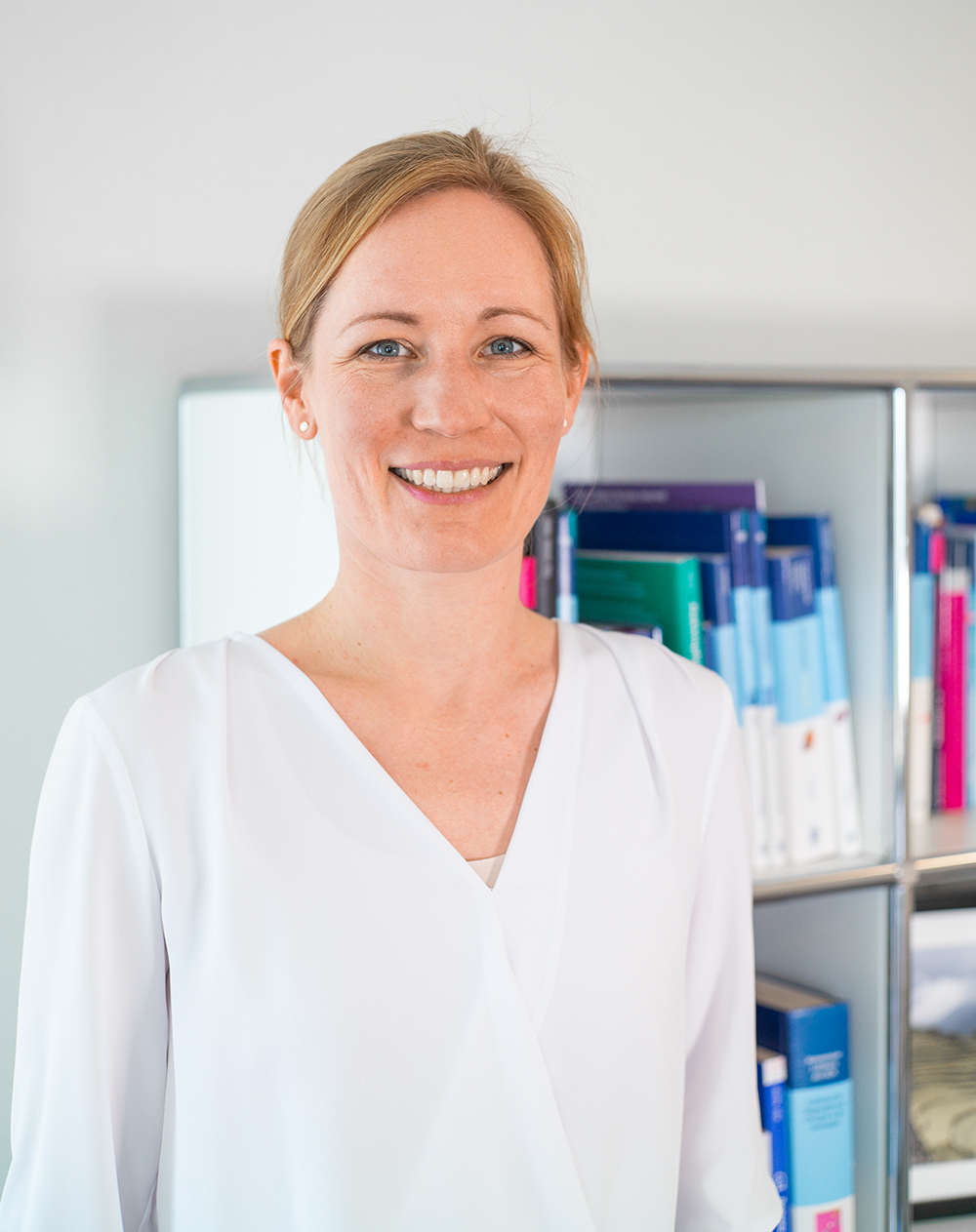 Porträtbild von Dr. med. Lisa Schönbrunn vor einem Buchregal
