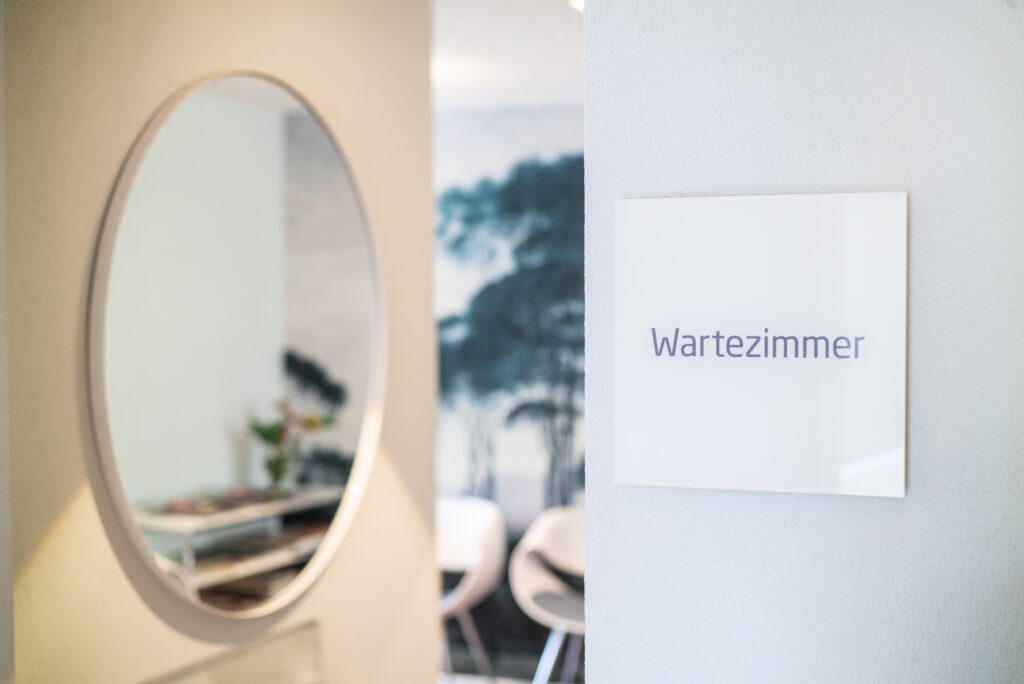 Schild zum Wartezimmer mit unscharfem Blick ins Wartezimmer